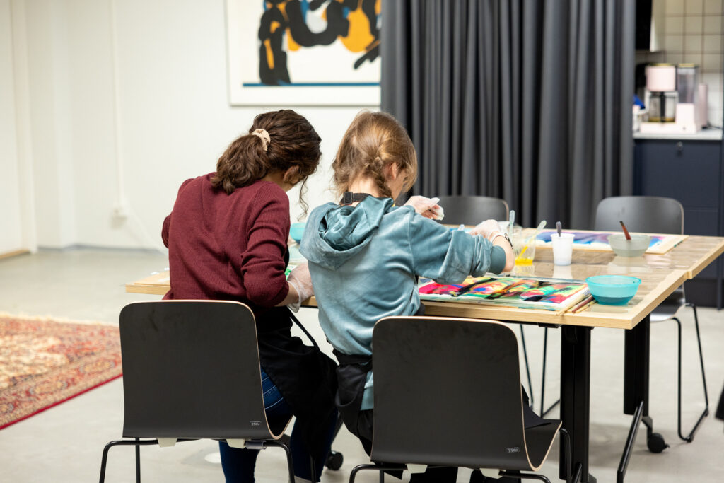 Kaksi lasta askartelee pöydän ääressä.